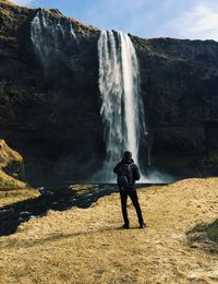 Man standing in front of waterfall