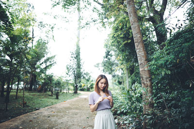 Portrait of smiling young woman standing against trees