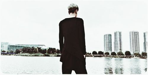 Rear view of woman standing by lake against clear sky