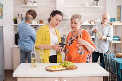 Portrait of smiling female friends holding food at home