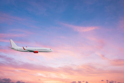 Low angle view of airplane flying against sky during sunset