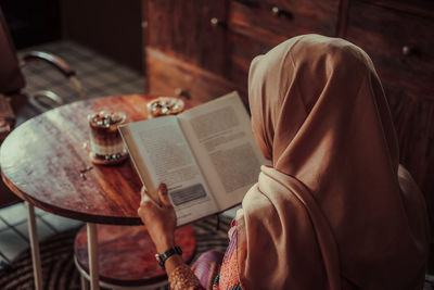 Midsection of woman reading book at home