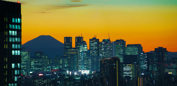 Illuminated cityscape against sky during sunset