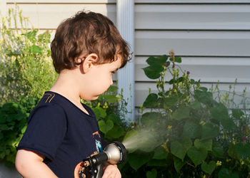 Little boy playing with a watering hose in the backyard