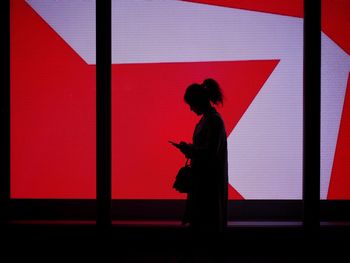 Side view of silhouette woman standing against illuminated wall