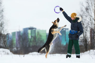 Man playing with dog on snow covered land