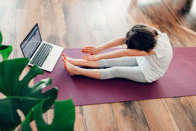 Cute little girl doing sports, stretching at home. child learns yoga at home online. 