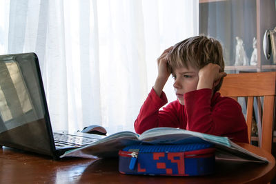 Boy sitting on table at home