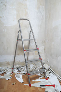 Ladder in corner of peeled wall at home