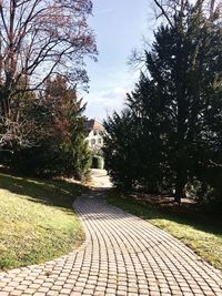 Footpath by street in city against sky