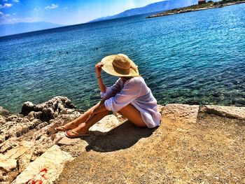 Woman sitting on rock looking at sea