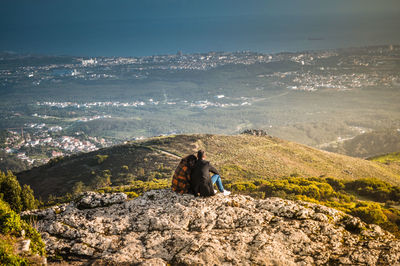 Woman sitting on rock against mountain range