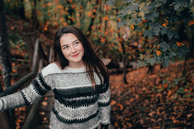 Portrait of young woman standing in forest during winter