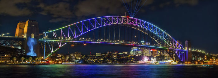 Illuminated bridge over river at night