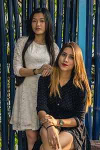 Portrait of smiling women standing against bamboo