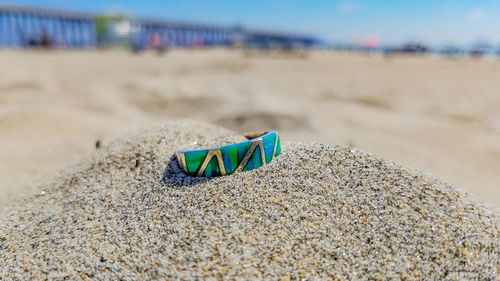 Close-up of shoes on sand at beach