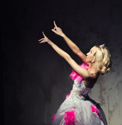 Beautiful young woman in pink and white wedding dress posing against wall