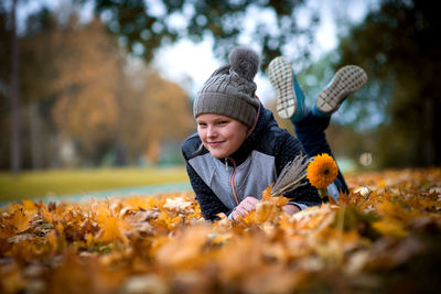 Portrait of smiling girl lying on leaves at park