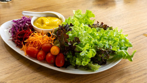 Mixed vegetables salad on white plate with caesar salad sauce, tomatos, 