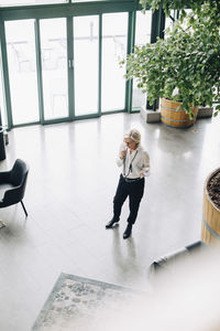 High angle view of businesswoman talking on mobile phone while standing in office