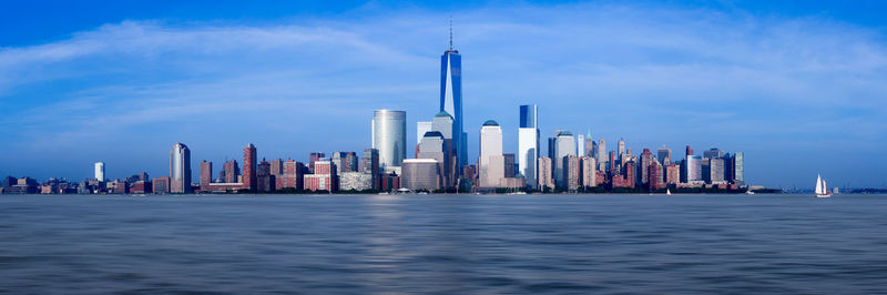 Sea by modern buildings in city against sky