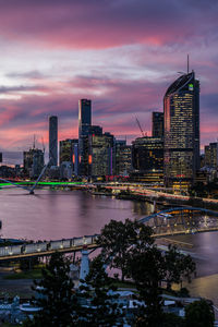 Illuminated buildings in city against sky during sunset