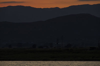 Scenic view of silhouette field against sky at sunset