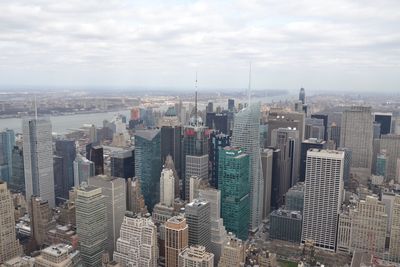 Aerial view of buildings in city against cloudy sky