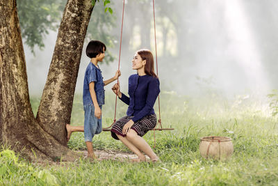 Full length of mother and daughter on swing