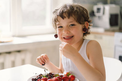 Cute beautiful little boy eating fresh cherry and strawberry.