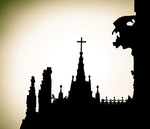 Low angle view of silhouette temple against building against clear sky