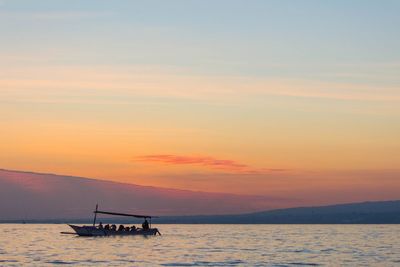 Silhouette boat in sea against sky during sunset