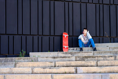 Teenager with headphones listening music while sitting on staircase.