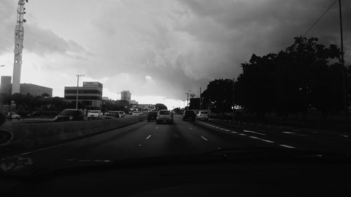 Cars on road against cloudy sky