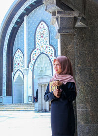 Full length of smiling woman standing against building