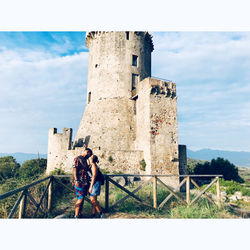 Woman standing by railing against sky