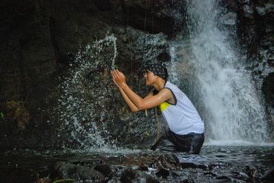 Man surfing on rock at waterfall