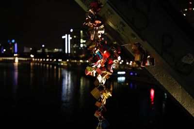 Illuminated padlocks on bridge over river in city at night