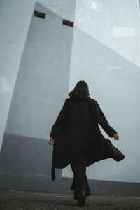 Rear view of woman walking against wall