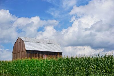 Barn on field against cloudy sky