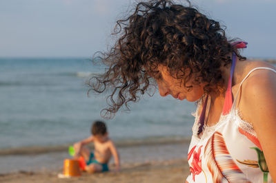 Side view of woman at beach against sky