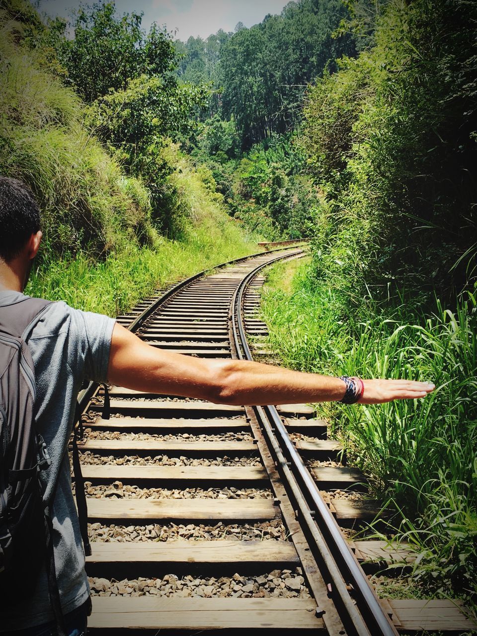 MAN ON RAILROAD TRACK AMIDST TREES