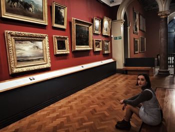 Full length portrait of woman sitting on floor