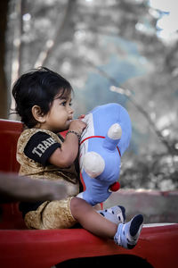 Cute boy playing with toy while sitting on bench