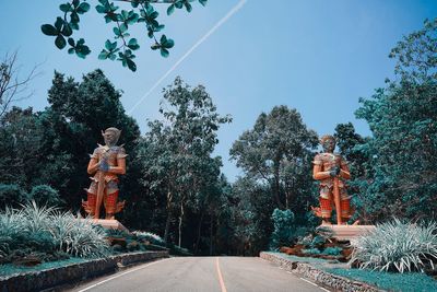 Statue amidst trees against sky during winter