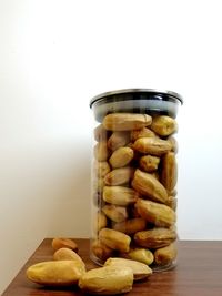 Close-up of bread in glass jar on table against white background