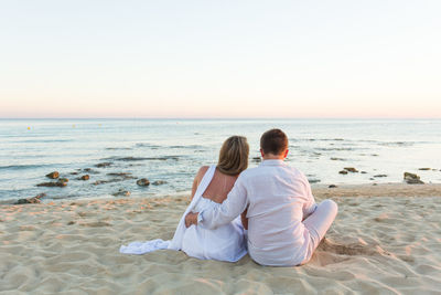 Rear view of couple sitting on beach