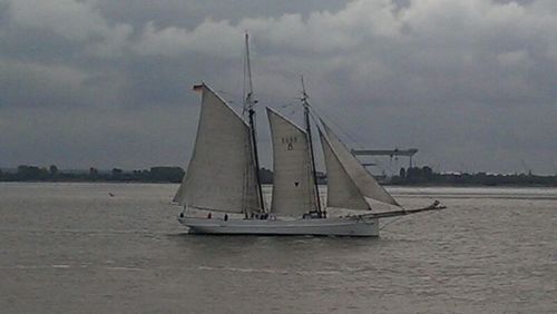 Boats in sea against cloudy sky