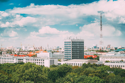 Trees and buildings in city against sky