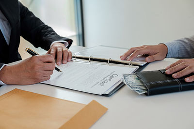 Midsection of man holding umbrella on table